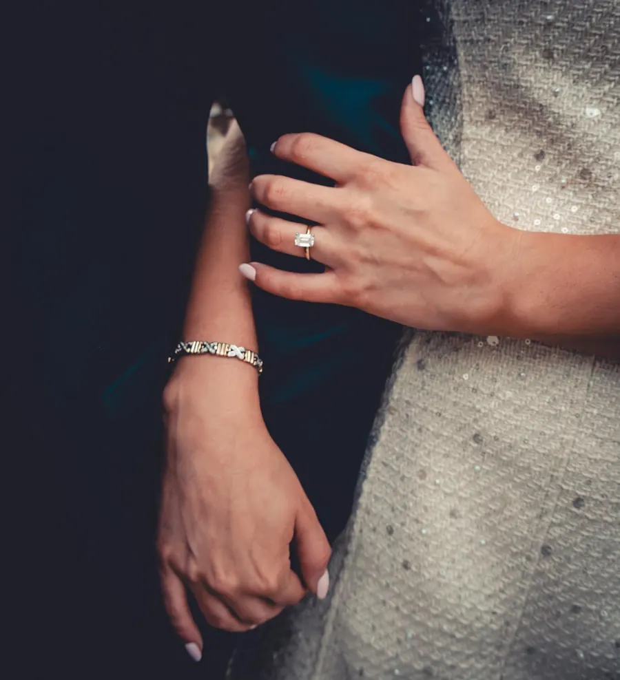 A bride's hand with an engagement ring resting on the groom's dark jacket